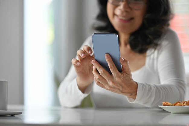 Carefree mature woman reading news online checking social media on smart phone Elderly technology concept