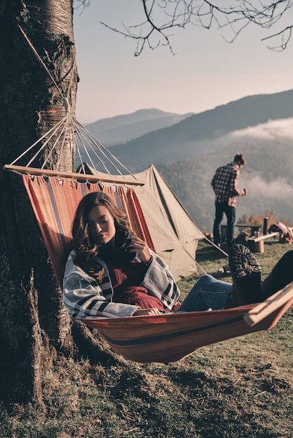 Carefree morning. Attractive young woman lying in hammock while camping with her boyfriend