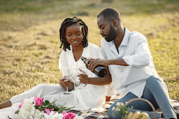 Carefree, relaxed couple enjoying the picnic together. Man poring wine into glass.