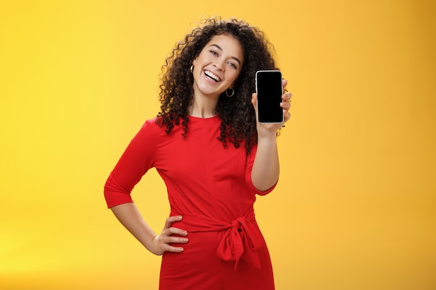 Carefree satisfied and happy attractive businesswoman presenting her best friend new mobile phone sh...
