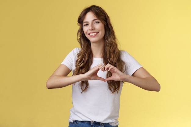 carefree tender attractive woman curly long hairstyle show heart sign near chest express love like s...