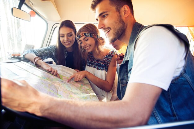 carefree weekend with friends. happy young people in a vintage van looking at a road map