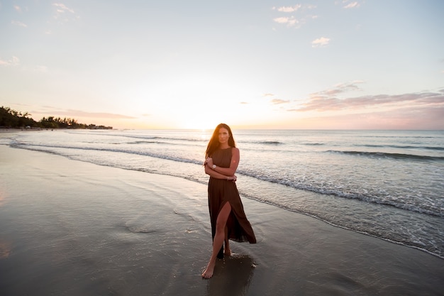 Carefree woman enjoying the sunset on the beach. Happy lifestyle