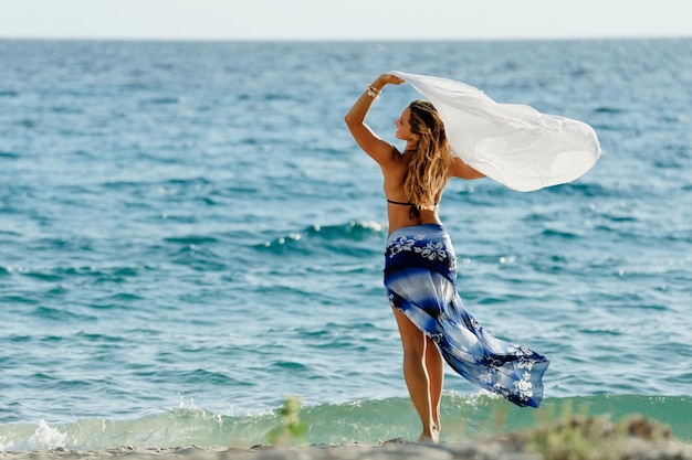 ビーチで夏の日に楽しんでいるスカーフを持つのんきな女性