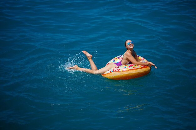 바다에서 편안한 하루를 즐기고 있는 평온한 어린 소녀 여성, 부풀릴 수 있는 고리에 떠 있는, 최고 전망. 바다 휴가 개념