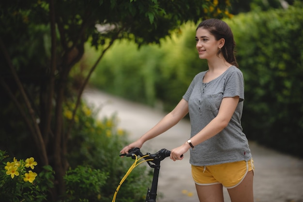 屋外のサイクルで運動しながらリラックスして楽しむ屈託のない若い女性