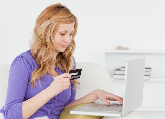 Careful woman sitting on a sofa is going to make a payment on the internet