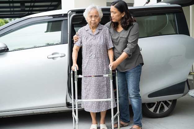 Caregiver daughter help and support asian senior or elderly old lady woman patient prepare get out her car