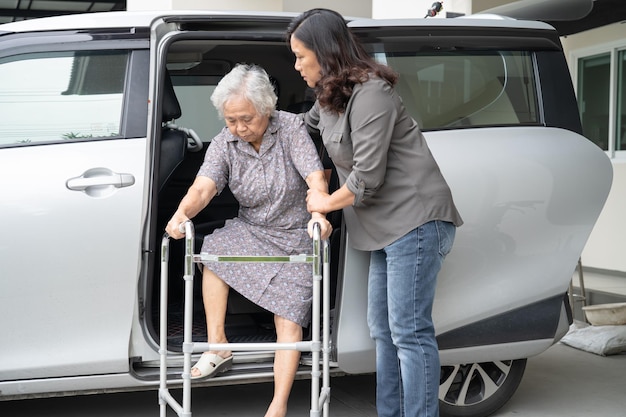 Caregiver daughter help and support asian senior or elderly old lady woman patient prepare get out her car