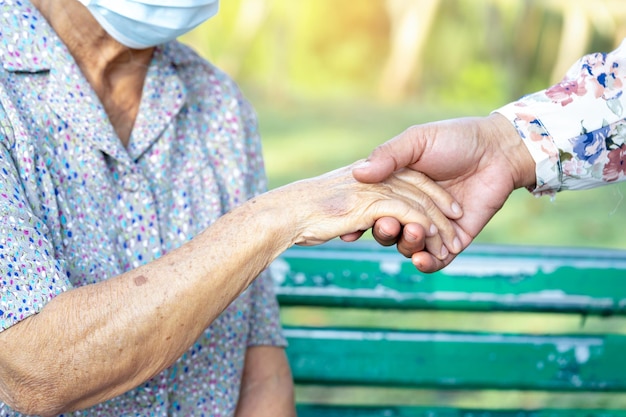 Caregiver daughter holding Touching hands Asian senior or elderly old lady woman patient with love, care, helping, encourage and empathy at nursing hospital ward, healthy strong medical concept.