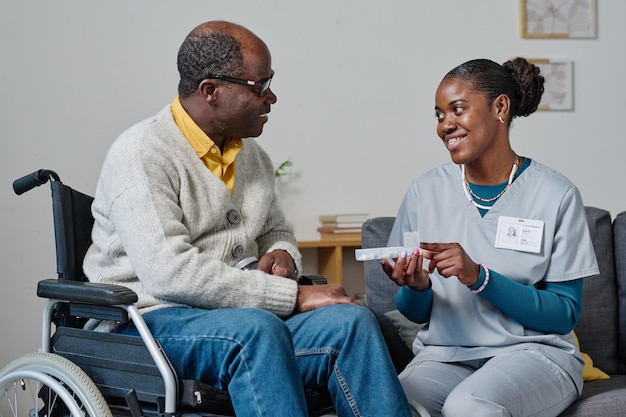 Caregiver giving pills to man with disability