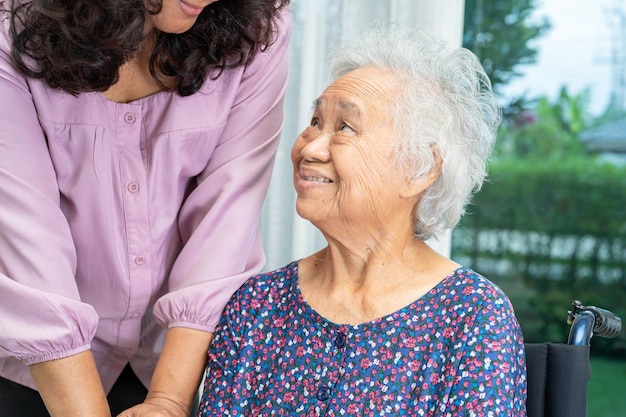 간병인은 요양병원 병동에서 휠체어에 앉아 있는 아시아계 노인 또는 노부인을 돕는 건강한 강력한 의료 개념
