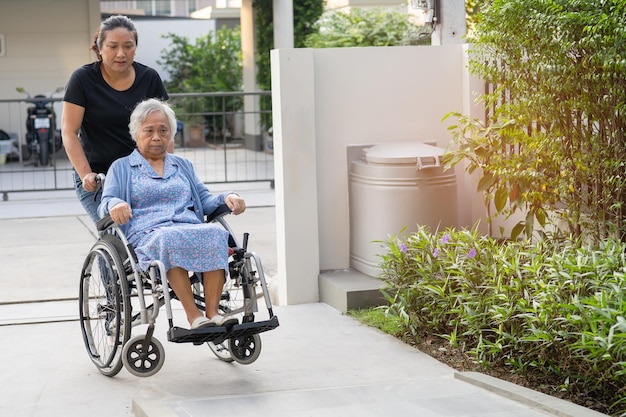 Caregiver help and care Asian elderly woman patient sitting on wheelchair to ramp in nursing hospital healthy strong medical concept