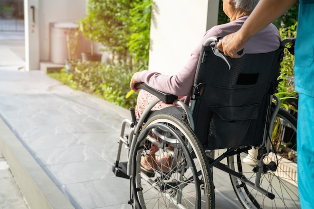介護者の助けとケア介護病院の健康的な強力な医療コンセプトでランプに車椅子に座っているアジアの年配の女性患者