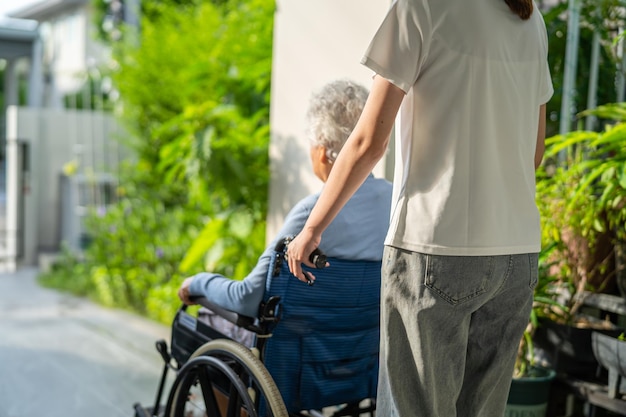 Caregiver help and care Asian senior or elderly old lady woman patient sitting on wheelchair to ramp in nursing hospital healthy strong medical concept