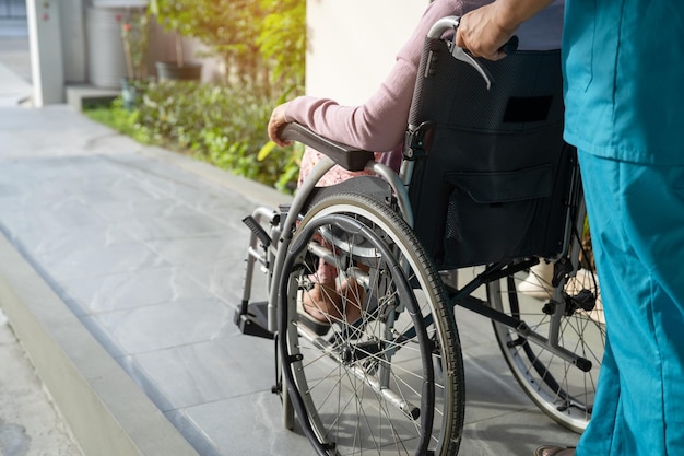 Caregiver help and care Asian senior or elderly old lady woman patient sitting on wheelchair to ramp in nursing hospital healthy strong medical concept