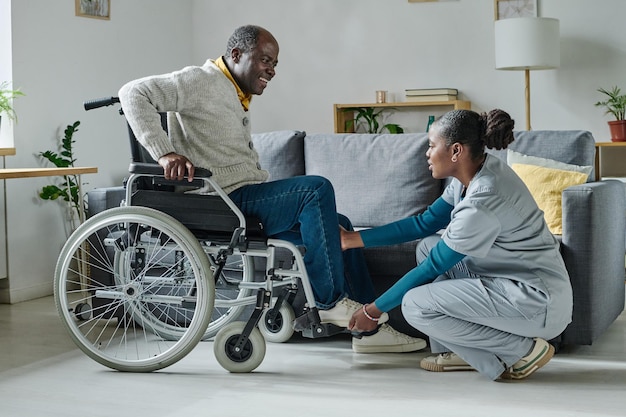 Caregiver helping man to sit on wheelchair