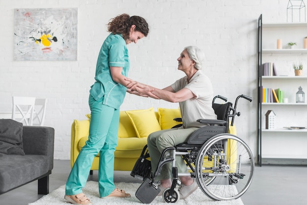 Photo caregiver helping senior female patient sitting on wheel chair