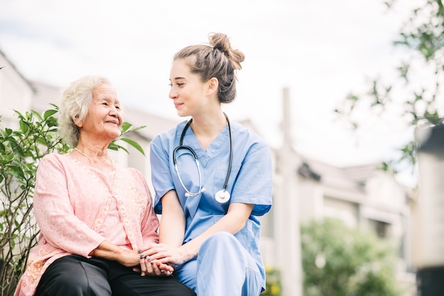 Caregiver holding hand of happy elderly woman 