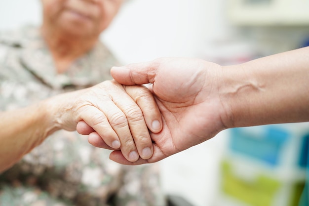 병원에서 아시아 노인 여성 환자의 도움과 보살핌을 손에 쥔 간병인