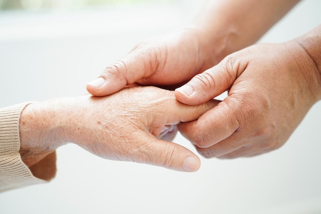 Caregiver holding hands Asian elderly woman patient help and care in hospital