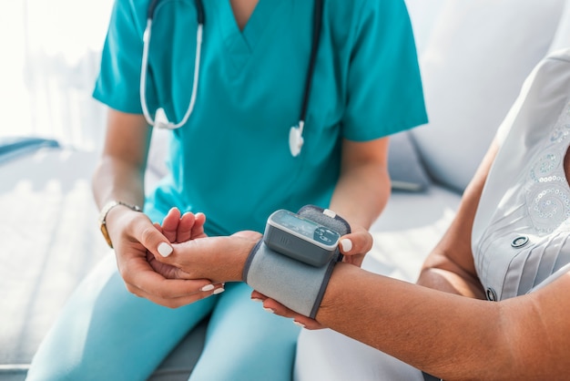 Caregiver measuring blood pressure of senior woman at home.