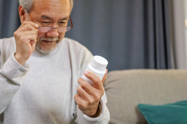 Caregiver nurse taking care of elderly grandfather sitting on sofa at home