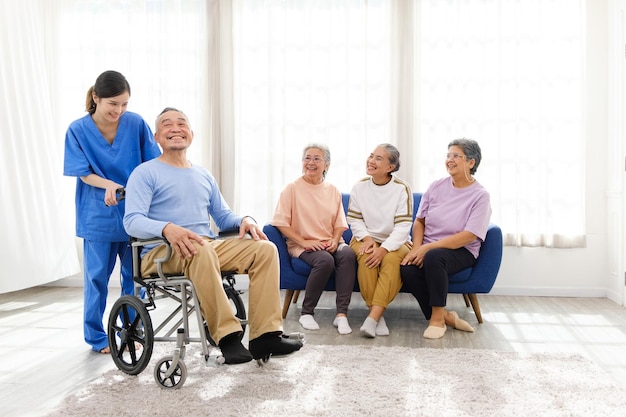 caregiver therapist stands with an asian senior sitting in a wheelchair with group of senior women