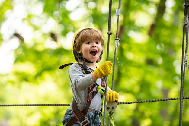 Cargo net climbing and hanging log Portrait of a beautiful kid on a rope park among trees Rope park