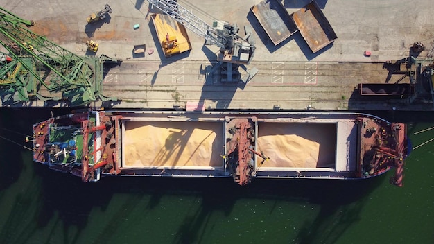 Photo cargo ship bulk carrier loading in port at sunset