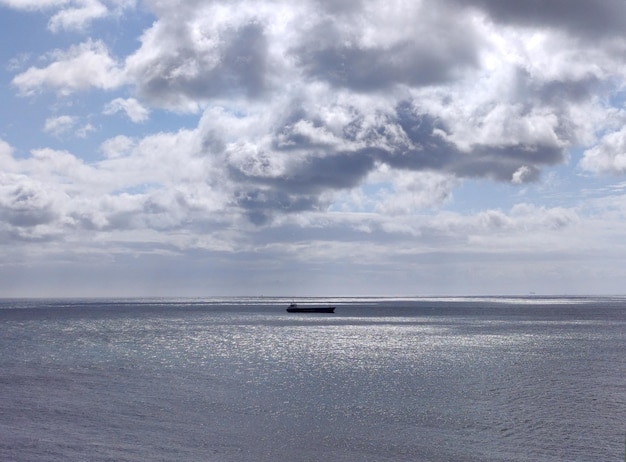 Cargo ship in the open sea White clouds over a stormy sky background and sea