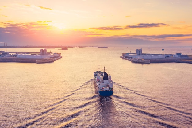 Cargo tanker with oil products sails in the harbor of an industrial city port at dawn in the morning aerial view