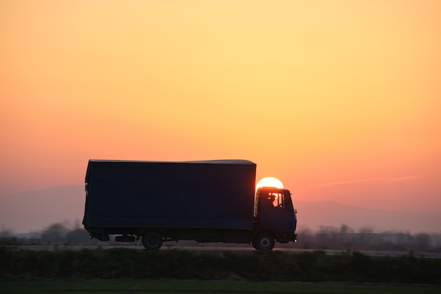 夕方に高速道路の運搬品を運転する貨物トラック配達輸送とロジスティクスの概念