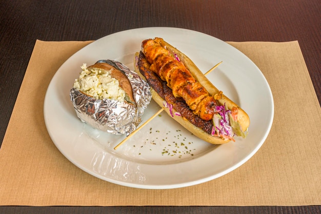 Caribbean sausage hot dog with fried ripe plantain and baked potato stuffed with fresh cheese