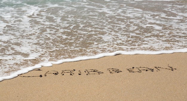 Caribbean written in sand with sea surf