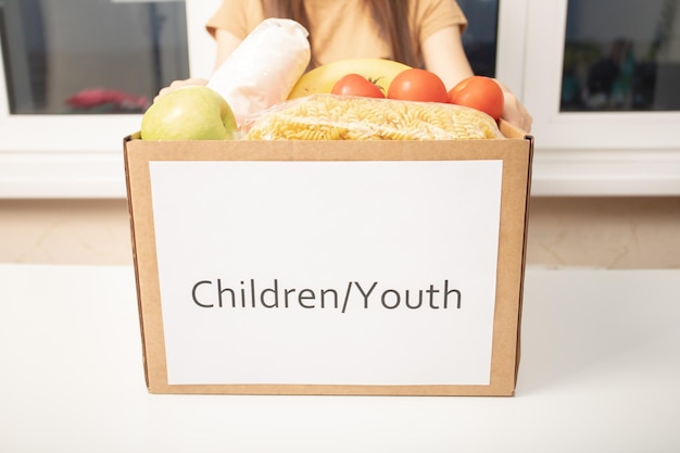 Caring for the children and teenagers A volunteer girl holds a box of food products