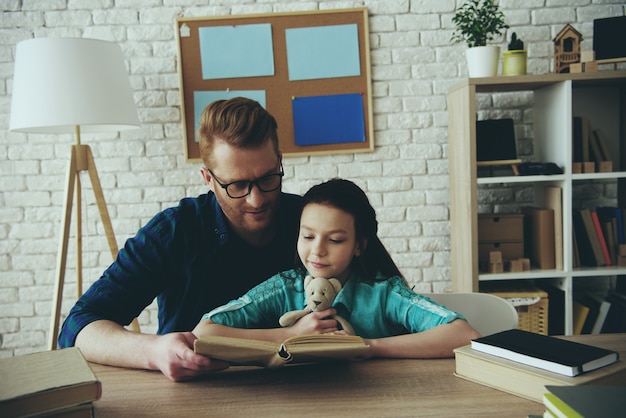 Photo caring dad reads book for daughter.
