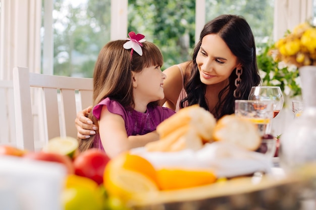 Mamma premurosa dai capelli scuri che abbraccia la sua adorabile figlia