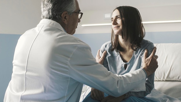 Photo caring doctor cheering up a patient at the hospital