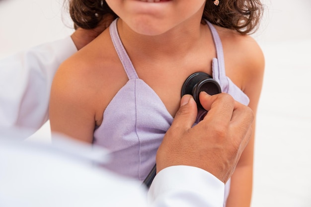 Caring doctor examining a girl in the office. Doctor examining lung and heart of little girl in office.