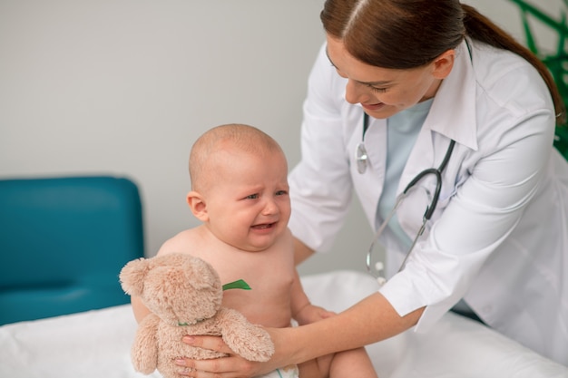 Caring doctor giving a toy to a crying baby