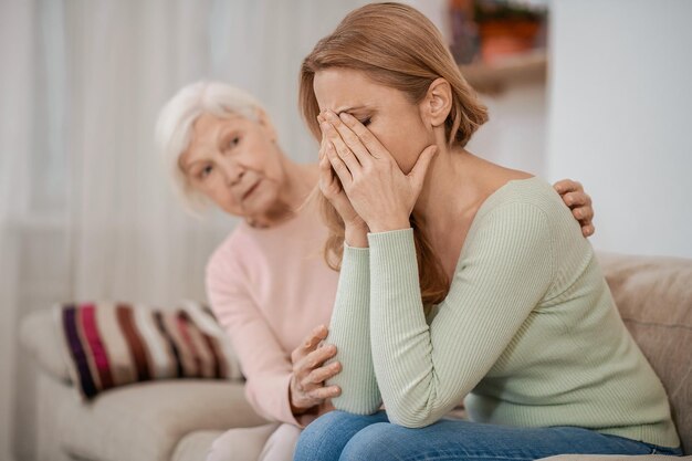 Caring elderly female parent consoling her daughter