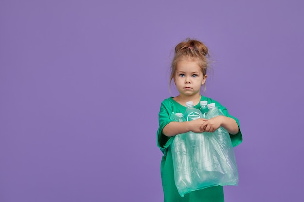 Caring for the environment. Little girl is separate plastic trash to recycle. Bright color studio space