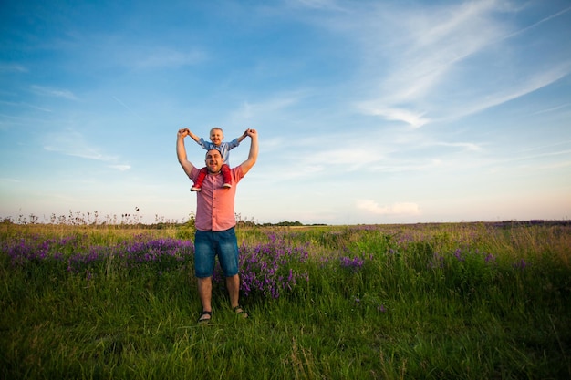 Caring father holding his little son on shoulders