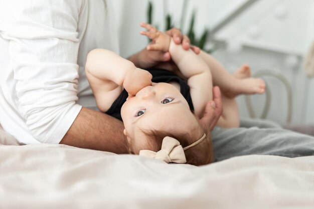 写真 思いやりのある父親が寝室のベッドで幼い娘と遊ぶ愛と思いやりの幸せな家族が一緒に時間を過ごすコンセプト