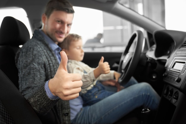 新しい快適な自動車で息子と一緒に座っている思いやりのある父