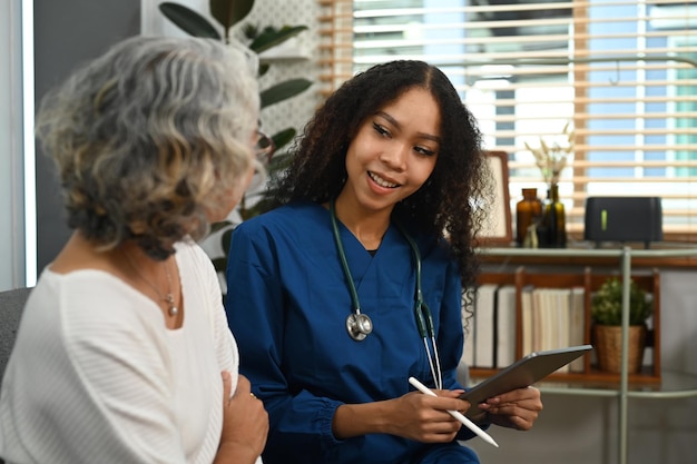 Photo caring female doctor explaining the medical results to the senior woman during home visit home health care service concept