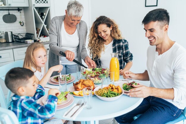 Foto padre latino premuroso che serve i suoi adorabili figli mentre fanno colazione insieme a casa