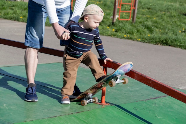 A caring and loving father teaches his threeyearold son to skateboard