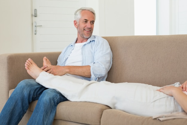 Caring man giving his partner a foot rub on the couch